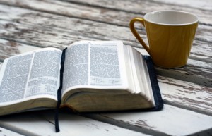 Bible and coffee cup on a weathered picnic table