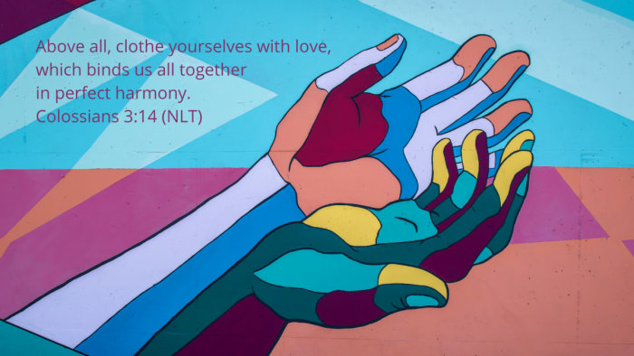 multi-color mural of open hands with quotation of Colossians 3:14, NLT